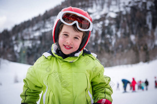 快乐儿童滑雪者准备乘坐下坡陡坡的画像。带着安全帽和护目镜的活泼儿童。冬季体育概念.