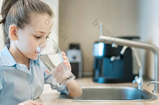 孩子们手里拿着一杯干净的水。白人小女孩在厨房用水龙头或水龙头喝水。倒入新鲜健康的饮料。<strong>好习惯</strong>正确的选择。环境概念。世界水日