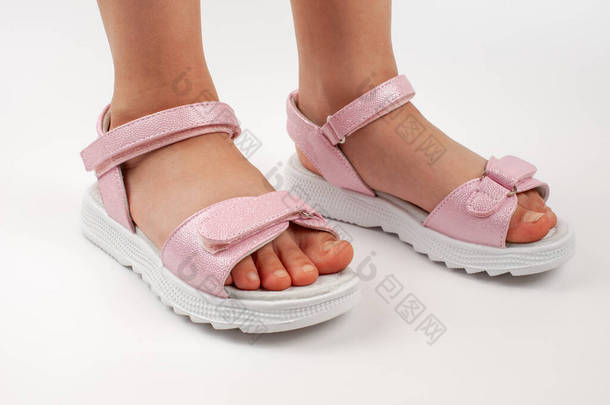 粉红色的童鞋是由闪亮的皮革制成的，有Velcro紧固件，平坦的白色鞋底与白色背景隔离。一双时髦的孩子穿上凉鞋去舒服地散步.