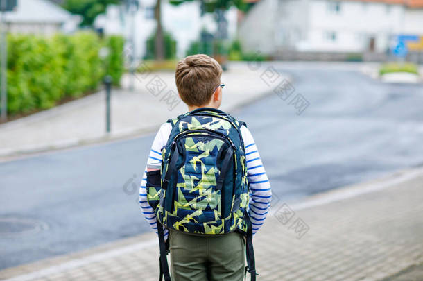 快乐的小男孩，带着背包和眼镜。小学生在去<strong>初中</strong>或高中的路上戴眼镜。在学校院子里兴奋的孩子。回学校去.