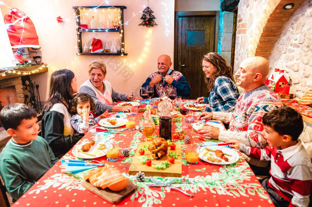 大型多代家庭在节日晚宴上玩得开心- -关于祖父母在家庭晚宴上与孩子们共进晚餐的冬季圣诞概念- -聚焦在中间的祖父