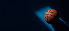 蓝色背景上有自然光的棕色新篮球运动。运动队的概念。横向体育主题海报、贺卡、头饰、网站和应用程序