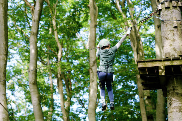 森林探险公园的学生。活泼的孩子,戴着头盔的孩子爬上了高绳的小径.敏捷的技巧和攀爬户外<strong>儿童娱乐</strong>中心.儿童和家庭的户外活动.