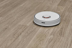 一个白色的机器人吸尘器在层压板地板上工作.聪明的房子机器人真空吸尘器自动清扫公寓.