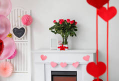 情人节礼物盒、订婚戒指和鲜花放在灯墙旁边的壁炉架上，房间里装饰着情人节的气氛