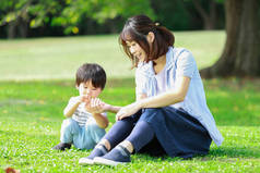 年轻的亚洲母亲和她的小儿子在公园里玩得很开心