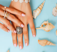 美丽的女人双手持有着珍珠和贝壳，奢侈珠宝概念板块的粉红色指甲