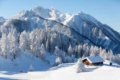 冬季自然背景。以传统木制小屋和高山为背景的雪景.