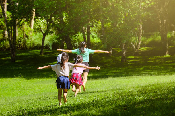两个可爱的女儿和妈妈<strong>一起跑</strong>着，张开双臂，好像在春天的花园里<strong>一</strong>样。后视镜看到年轻的母亲在公园里和孩子们玩耍。快乐的家庭在公园里玩得开心.