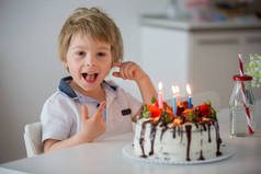 四岁的金发孩子，学龄前男孩，在家里用草莓和巧克力自制的蛋糕庆祝生日
