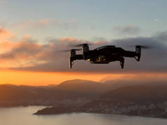 Quadcopter soars over the city on the seashore at the foot of the mountains. High quality photo