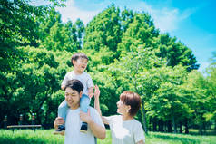 Parents and child playing happily while piggybacking in the park