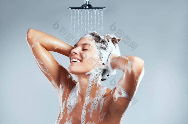 This is what makes me truly <strong>happy</strong>. a young woman washing her hair in the shower against a grey backg