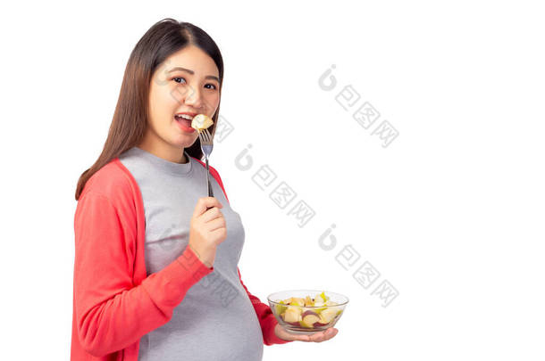 怀孕的年轻亚洲女人吃新鲜的<strong>水果</strong>沙拉，<strong>水果</strong>沙拉是婴儿或胎儿的健康食品。怀孕的母亲拿着一袋<strong>水果</strong>沙拉.怀孕、产前、母性、保健概念