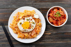 泡菜炒饭炒鸡蛋在顶部和新鲜泡菜卷心菜在一个碗上的木质背景, 顶部视图, 韩国菜