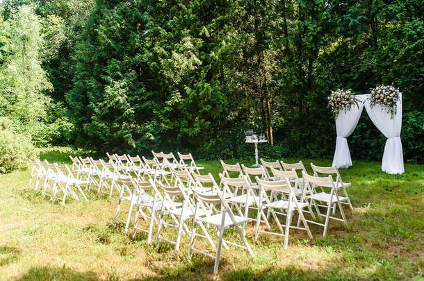 婚礼拱门装饰在户外的布和花。漂亮的婚礼布置好了。婚礼在花园里的绿色草坪上举行.节日装饰的一部分,鲜花的布置.高质量的照片