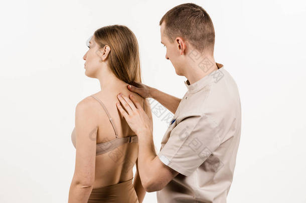 对理疗师或脊椎按摩师进行人工治疗。整形外科医生检查女性的颈部和头部。人工矫正脊椎和颈椎区域。白人背景的康复治疗