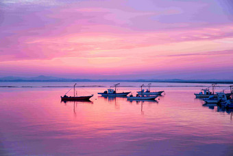 紫色太阳日落海上渔船风景摄影图