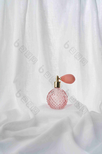 粉红香水瓶白色布料背景