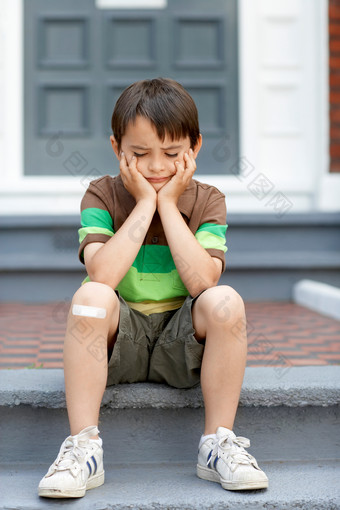 膝盖受伤的小男孩摄影图