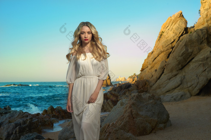 海滩岩石旁的白裙女子