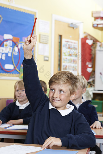 男孩课堂上举起手中的铅笔