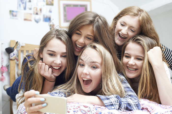 一群女孩趴在床上开心看手机