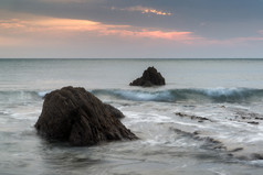 夜幕夕阳中海水中的岩石