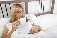 简约床上喝茶的女人摄影图