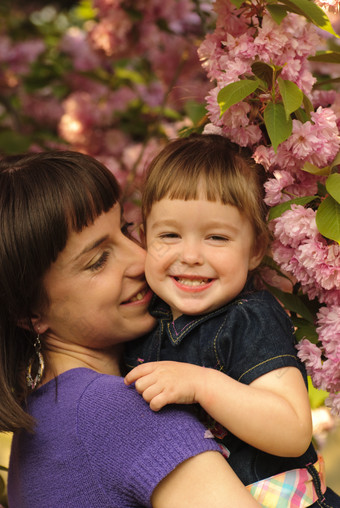 花朵边微笑的母女摄影图