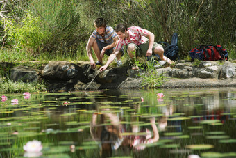 绿色调水塘边的男孩们摄影图