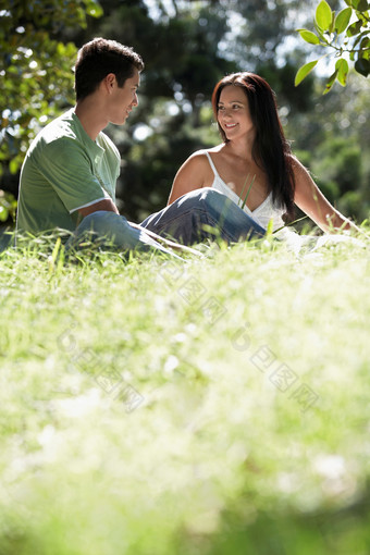 深色调坐草地上的情侣摄影图