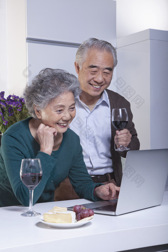 爷爷<strong>奶奶</strong>老人夫妻看电脑视频微笑喝红酒