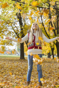 秋季金发女性站在落叶上