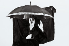 暗色调打伞的小丑摄影图