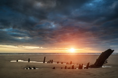 暗色调夕阳下的海滩摄影图