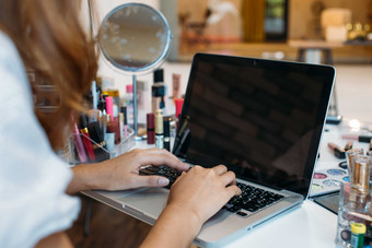 化妆桌上用电脑办公的女人摄影图