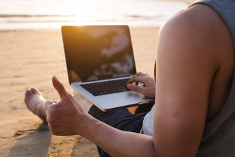 沙滩上玩电脑的男人摄影图