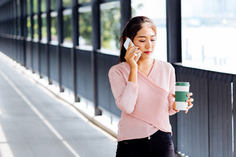 女子<strong>端着</strong>杯子打电话摄影图