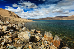 蓝天白云湖边石堆摄影图