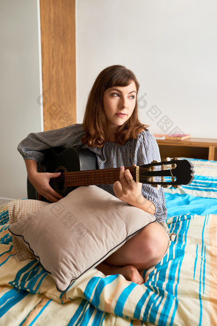 在卧室里弹吉他放松的女生
