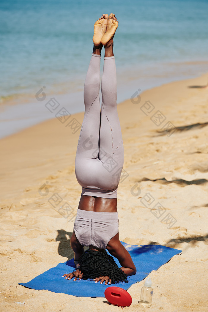 在海滩倒立的瑜伽女子