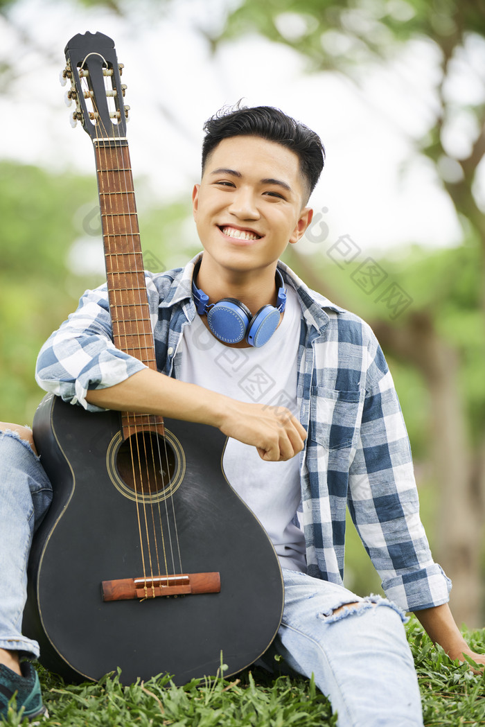 在草坪上休闲弹吉他的男青年