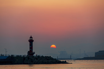 深红落日余晖海边灯塔摄影图