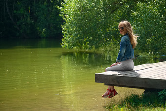 森林湖泊旁坐着个小女孩