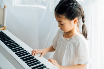 可爱女孩坐着弹钢琴