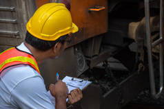 亚洲工程师戴安全帽、检查列车维修的图片