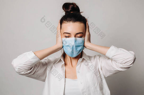 情绪震惊的女医务人员戴着外科口罩，由于大流行病的威胁而陷入恐慌