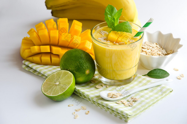 Yellow smoothie in glasses with mango and tropical fruits