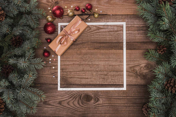白色框架的顶部看法, 圣诞节礼物和闪亮的华而不实在木表面用冷杉小枝和松树锥体